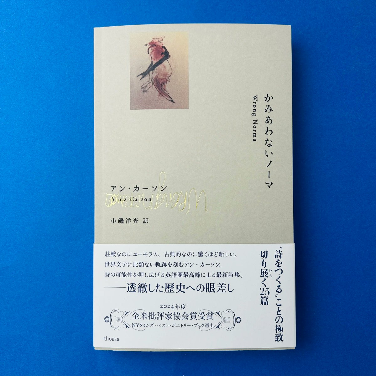 青い背景に置かれた『かみあわないノーマ』の日本語版。表紙にきつねのような動物の絵