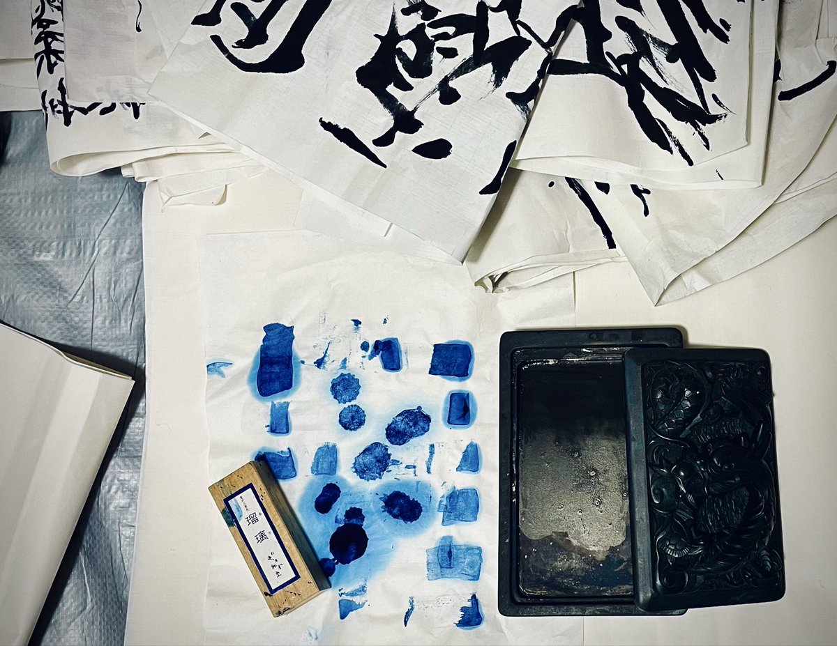 書いた半紙と、墨のあとがついた紙、使ったあとの硯