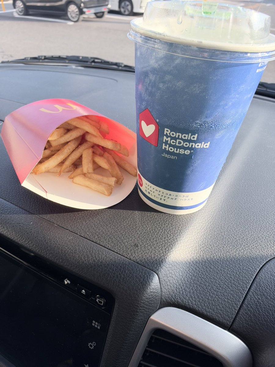 車のダッシュボードに置いたマックフライポテトとドリンクの紙コップ