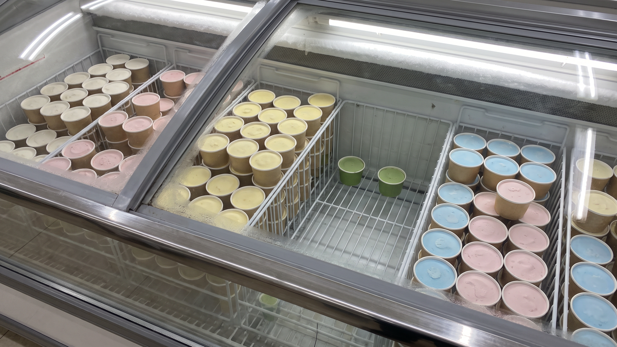 スーパーのアイス売り場の冷凍ケースに、緑色のカップアイスが少しだけ残っている場面