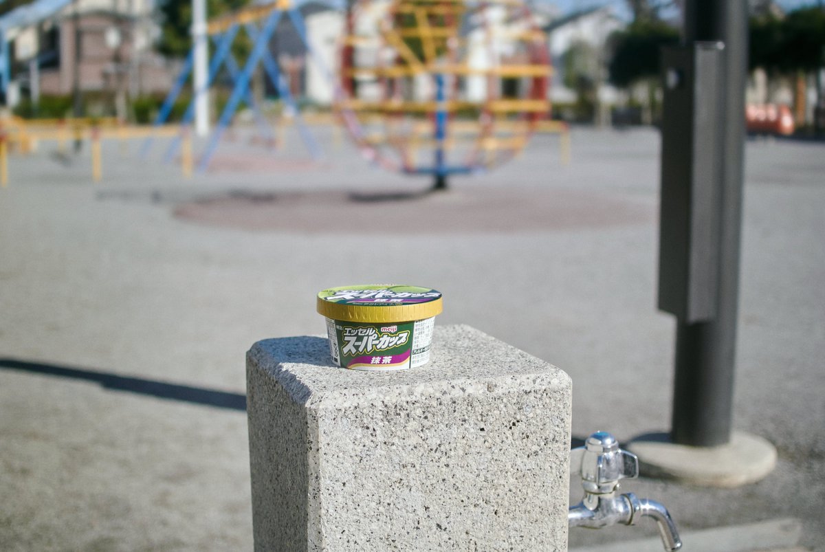公園の水飲み場の台の上に置かれた、スーパーカップ抹茶のカップ