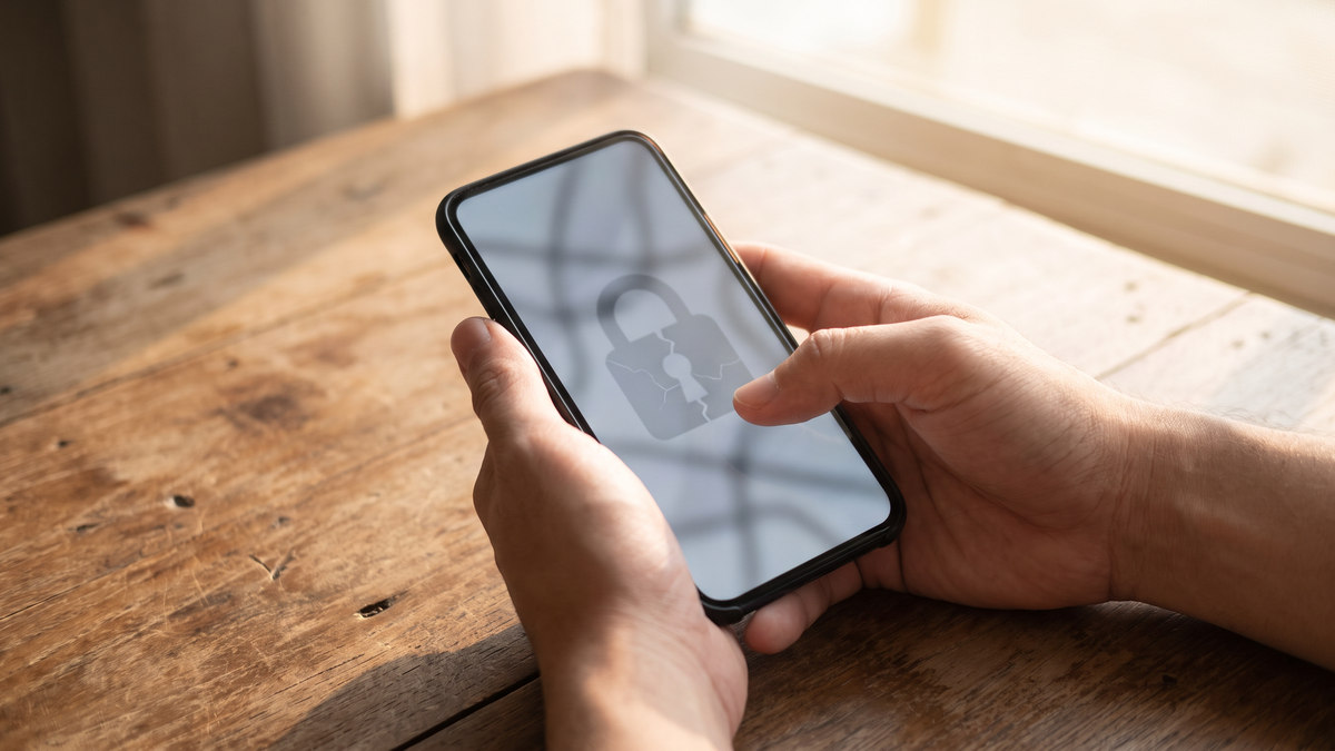 スマートフォンの画面に鍵が壊れたマークが出ている手元